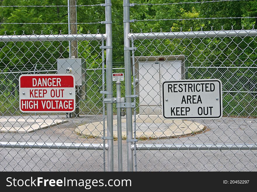 A chain link fence and warning signs barring access to a restricted area. A chain link fence and warning signs barring access to a restricted area