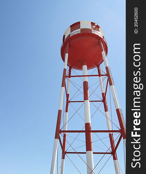 A red and white water tower reaches toward the sky. A red and white water tower reaches toward the sky