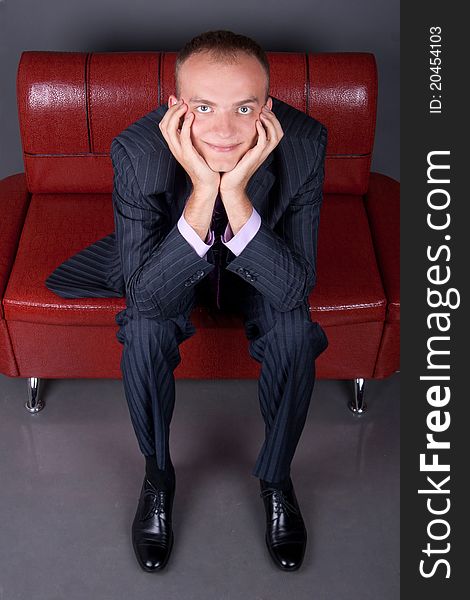 Thoughtful Guy In A Suit Sitting On A Red Couch