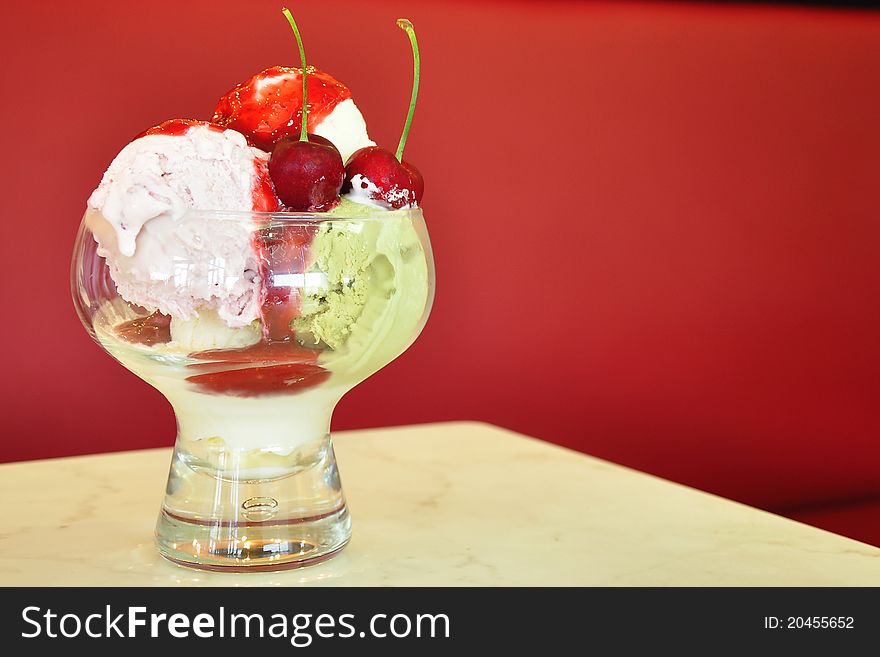 Three scoops of ice cream with cherry in a bowl