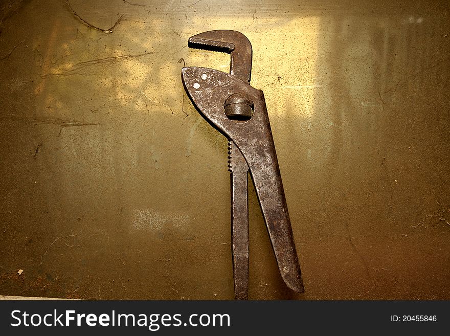 Old pipe wrench isolated on dirty background
