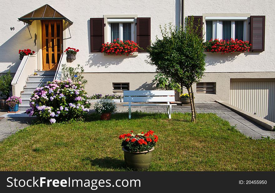 Beatiful yard with flowers and bench in front of the house. Beatiful yard with flowers and bench in front of the house