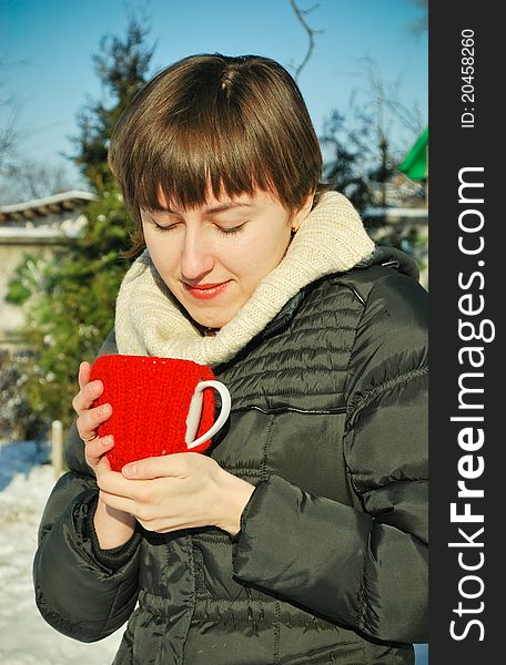 Young woman drinking hot tea outdoors in a snowy garden