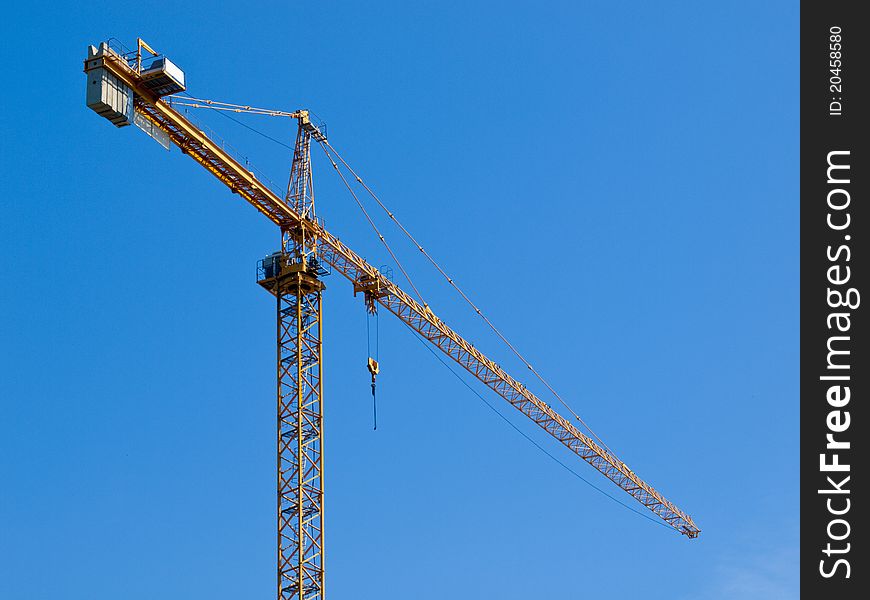 Yellow construction crane against clear blue sky. Yellow construction crane against clear blue sky