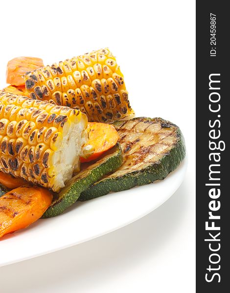 Grilled vegetables: zucchini, corn and carrots. Lie on a white plate. Isolated on a white background. Grilled vegetables: zucchini, corn and carrots. Lie on a white plate. Isolated on a white background.