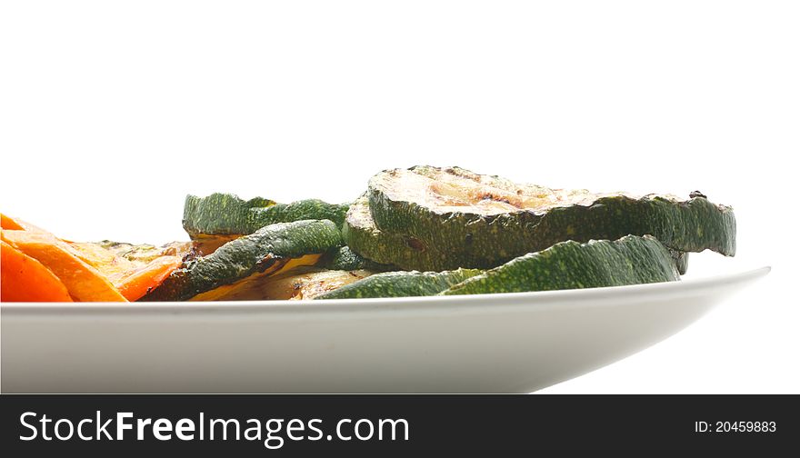 Grilled vegetables: zucchini and carrots. Lie on a white plate. Isolated on a white background. Grilled vegetables: zucchini and carrots. Lie on a white plate. Isolated on a white background.