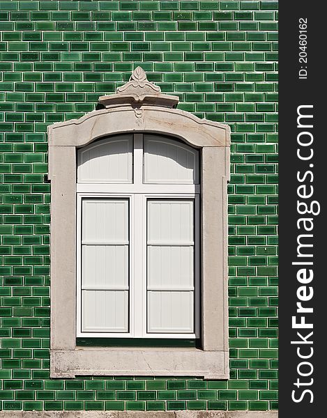 Traditional stone decorated window in a green tile background, Algarve, Portugal. Traditional stone decorated window in a green tile background, Algarve, Portugal