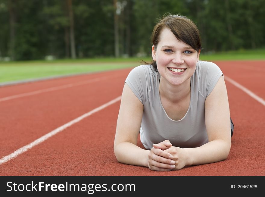 Young woman stretching on running track