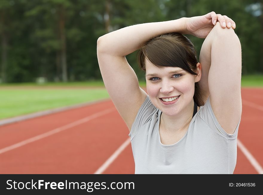 Young woman stretching on running track