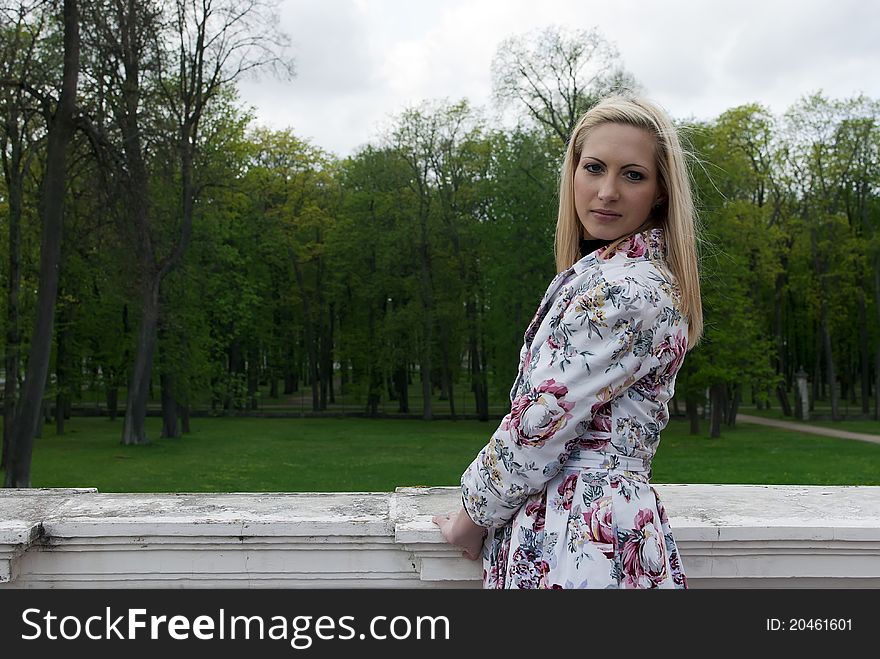 Blonde girl standing against a background of park, portrait