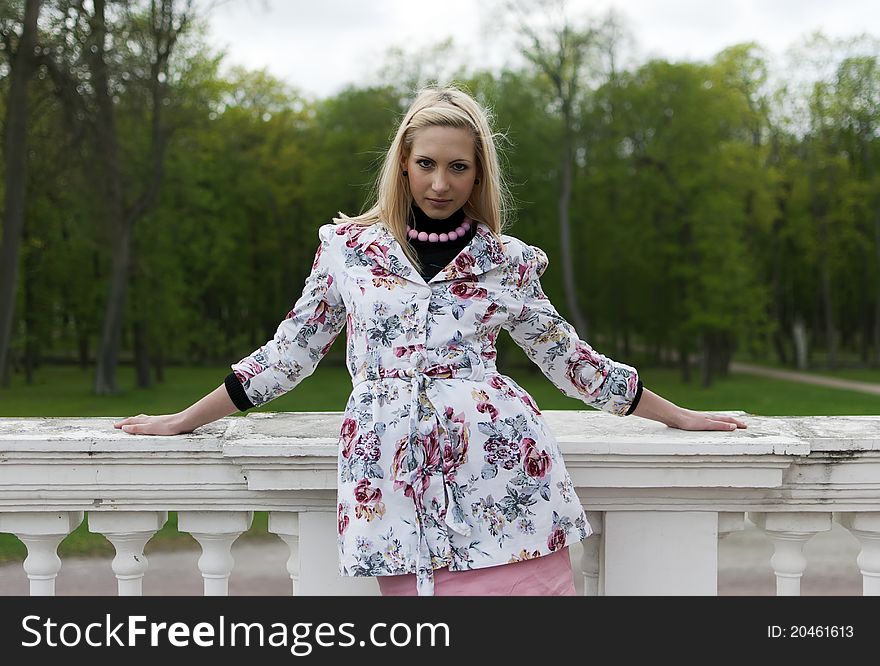 Blonde girl is leaning on old railing against the park. Blonde girl is leaning on old railing against the park