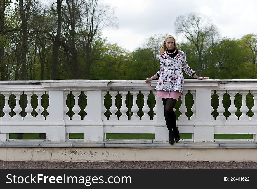 Blonde girl is leaning on old railing against the park. Blonde girl is leaning on old railing against the park