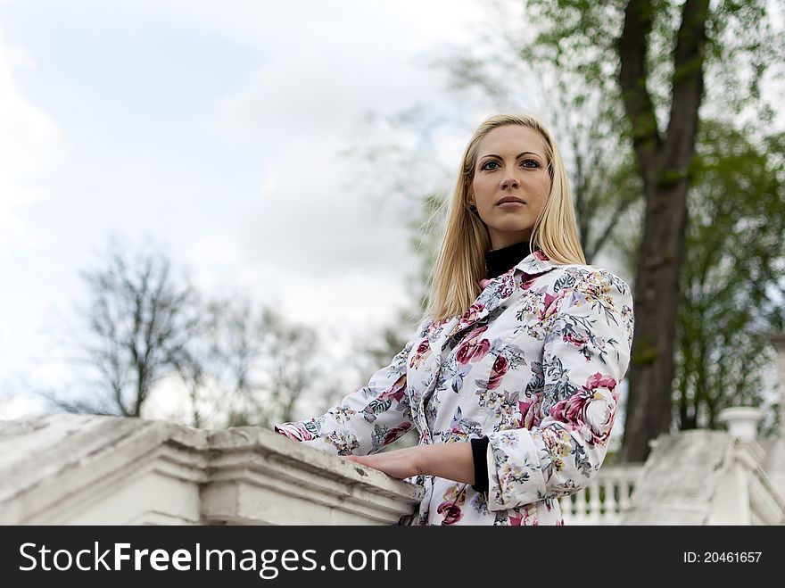 Blonde girl is leaning on old railing against the park. Blonde girl is leaning on old railing against the park