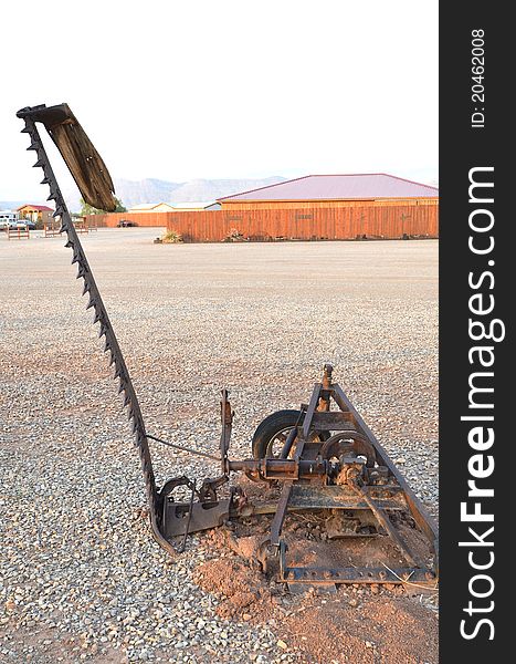 An antique piece of farm equipment used for cutting wheat or stalks. An antique piece of farm equipment used for cutting wheat or stalks.