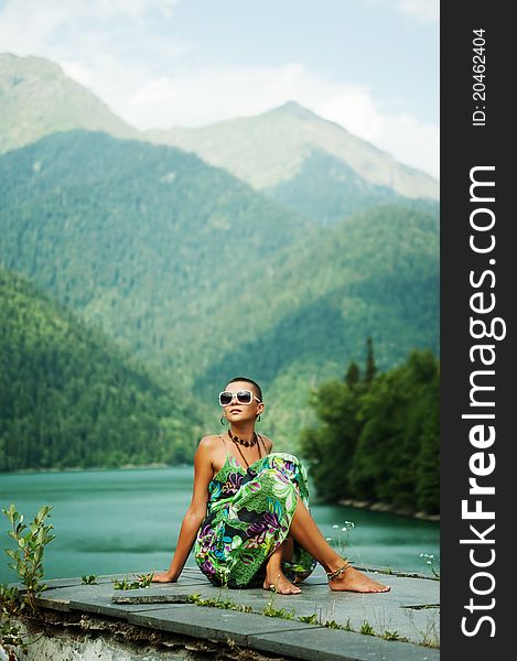 Beautiful young girl in mountains on the lake rejoices  the space of freedom