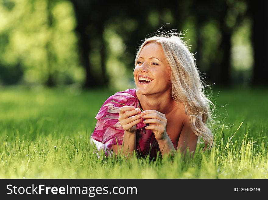 Blonde lying on green grass ang laughing