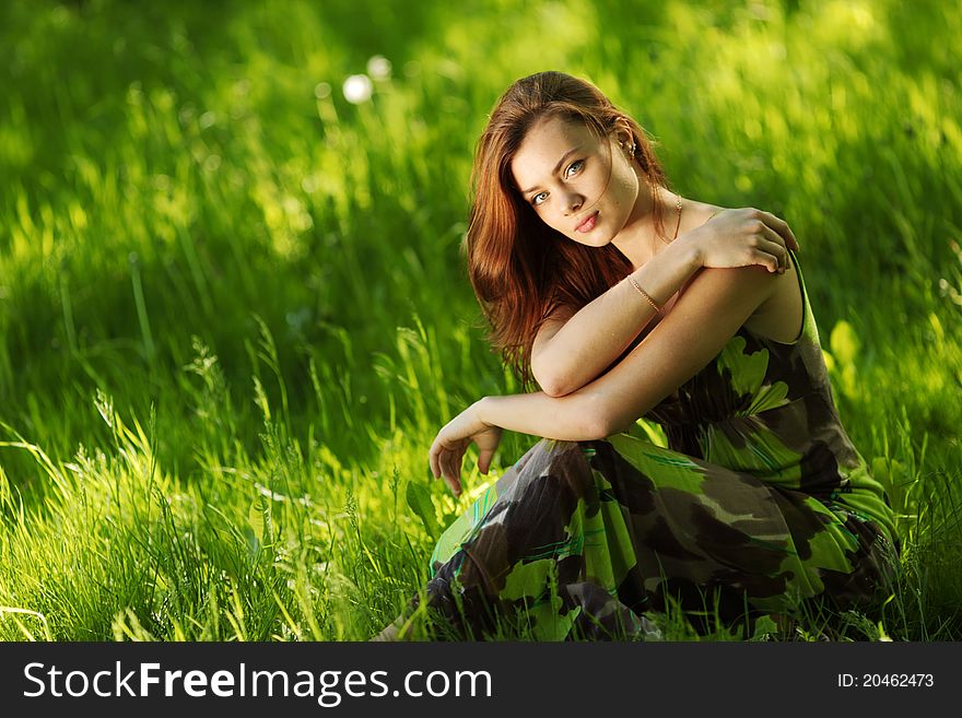 Beautiful brunette sitting on green grass