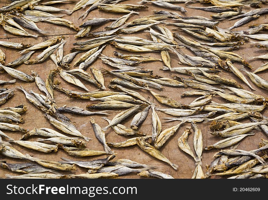 Small dry fishes drying on sun on burlap fabric