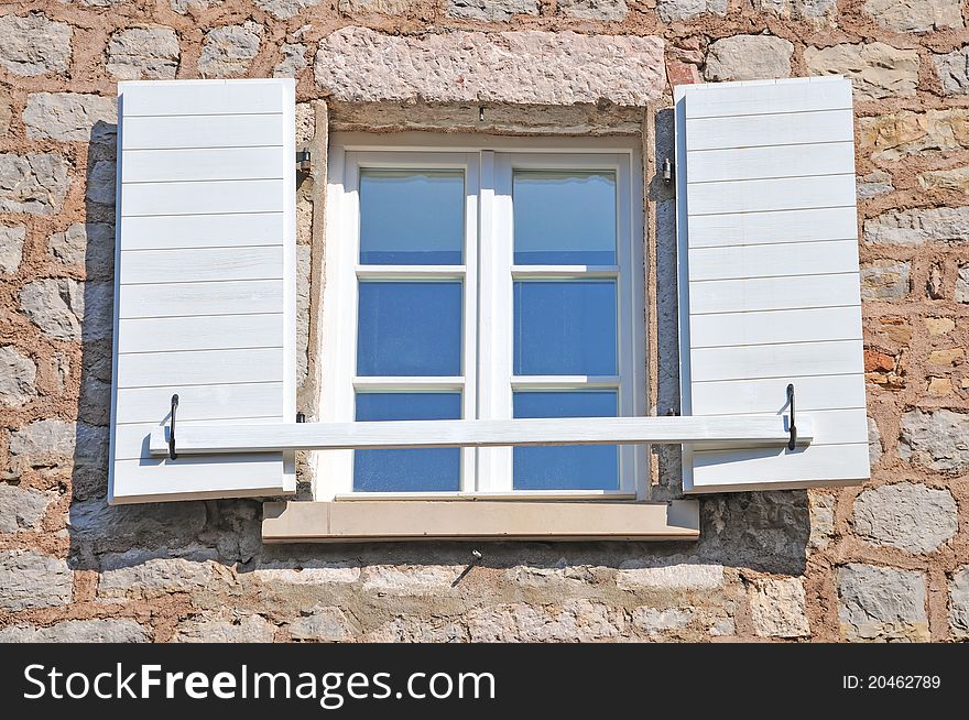 Open Mediterranean window, with stone wall and reflection of the blue sky