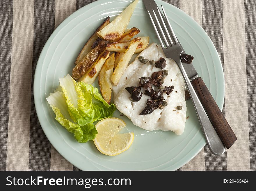 Cod with capers, black olives and potato chips with lettuce. Cod with capers, black olives and potato chips with lettuce