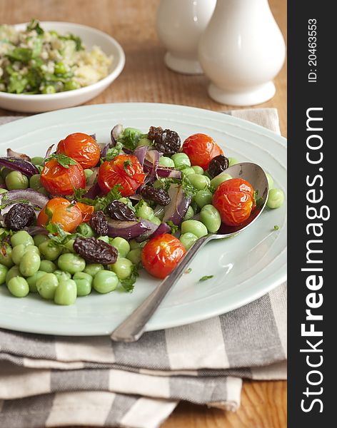 Broad bean, cherry tomato and raisin salad on a plate. Broad bean, cherry tomato and raisin salad on a plate