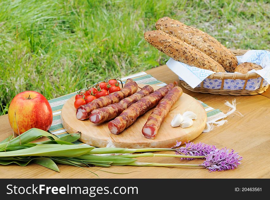 Domestic bread, tomatoes, sausage, apple, garlic in the nature. Domestic bread, tomatoes, sausage, apple, garlic in the nature