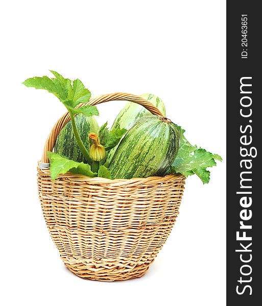 Fresh zucchini fruits with green leaves and flower in the basket on white background