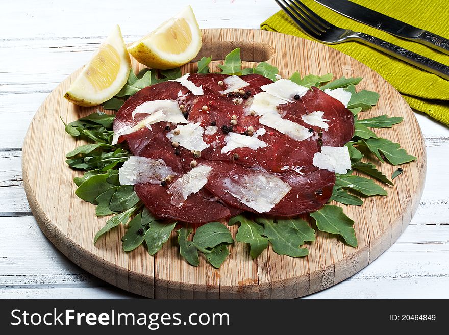 Italian bresaola seasoned with flakes parmesan, olive oil an pepper served on a bed of rocket