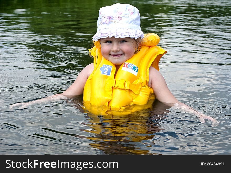 The child dressed in a life jacket studies to float. The child dressed in a life jacket studies to float