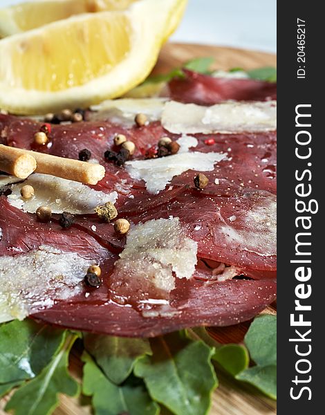 Italian bresaola seasoned with flakes parmesan, olive oil an pepper served on a bed of rocket