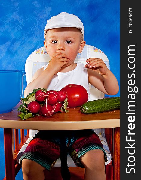 Short boy playing with vegetables against the blue mosaic background. Short boy playing with vegetables against the blue mosaic background