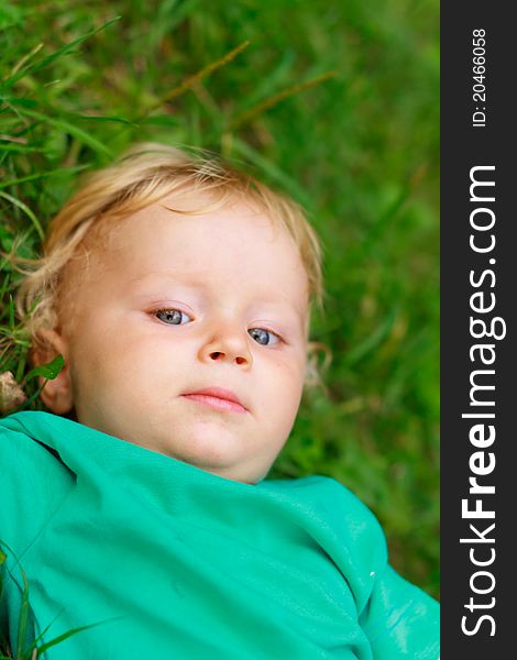 Baby with arrogant face expression laying on grass. Baby with arrogant face expression laying on grass