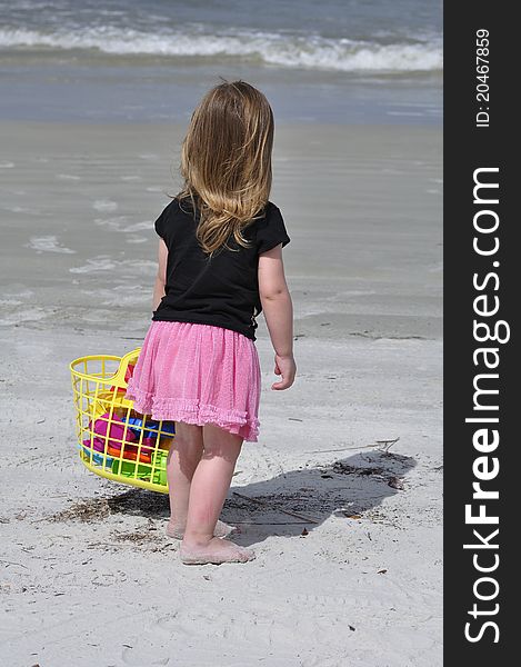 Little girl standing by the water at a beach in Florida holding a beach bag. Little girl standing by the water at a beach in Florida holding a beach bag.