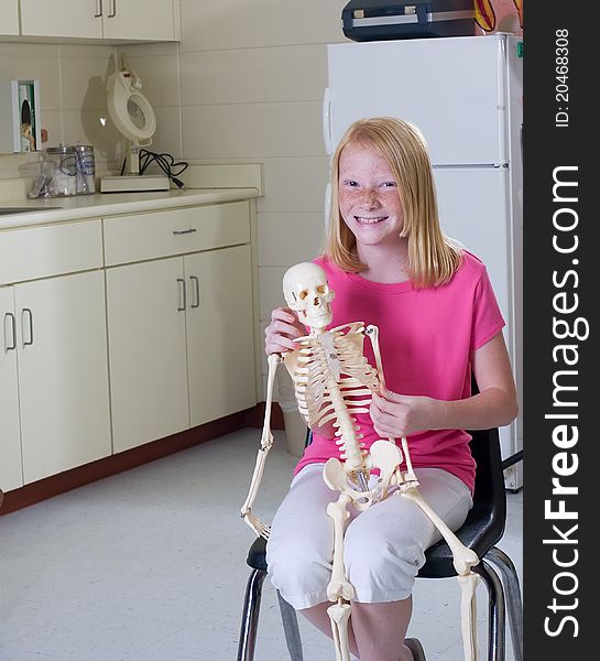 Young girl holding medical skeleton in pediatric office