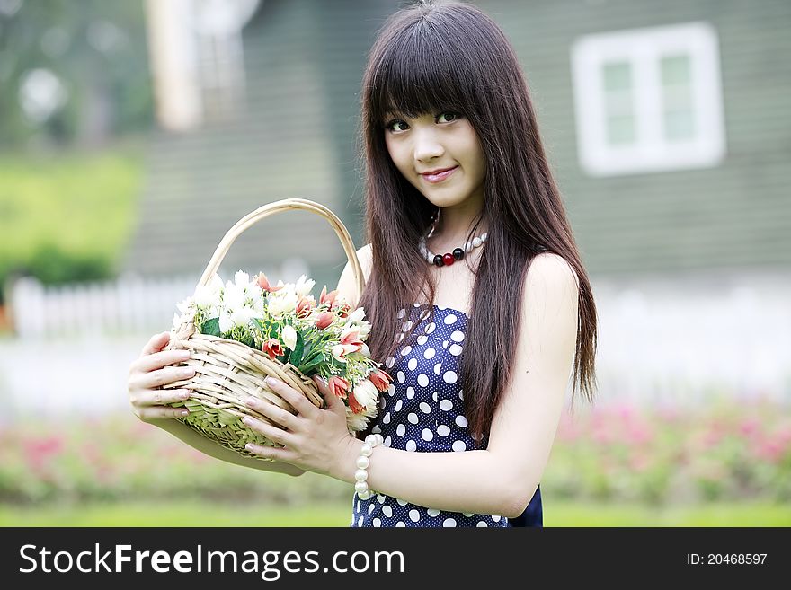 Attractive Asian girl holding a basket of flowers outdoor portrait. Attractive Asian girl holding a basket of flowers outdoor portrait.