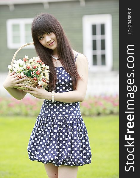 Asia beauty holding a basket of flowers posing outdoor in summer. Asia beauty holding a basket of flowers posing outdoor in summer.