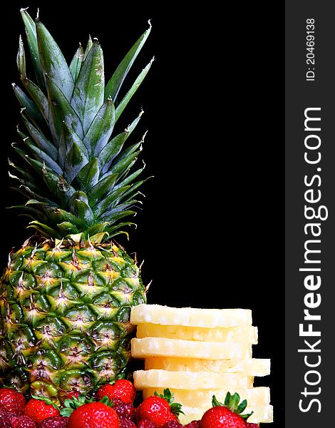 Pineapple with berries and raspberries against black background