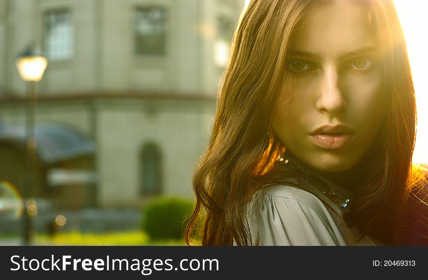 Portrait of a beautiful girl posing at the city street in sunset back light