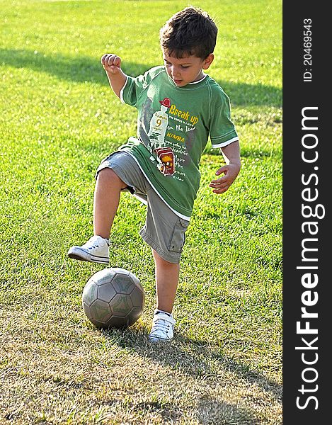 Young boy tackling a rubber ball, enjoying a game of football outdoors in the park. Young boy tackling a rubber ball, enjoying a game of football outdoors in the park.
