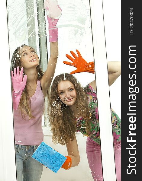 Attractive girls washing the window with mops looking throu window