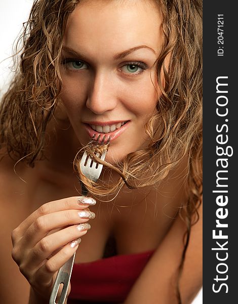 Portrait of a pretty young female winding her curly hair on fork. Portrait of a pretty young female winding her curly hair on fork