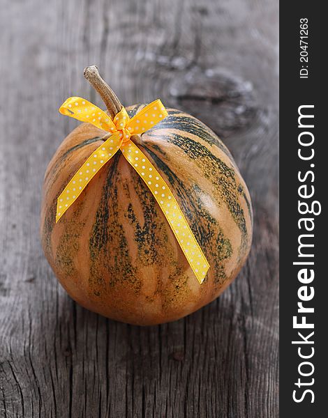 Pumpkin decorated with ribbon on the wooden background