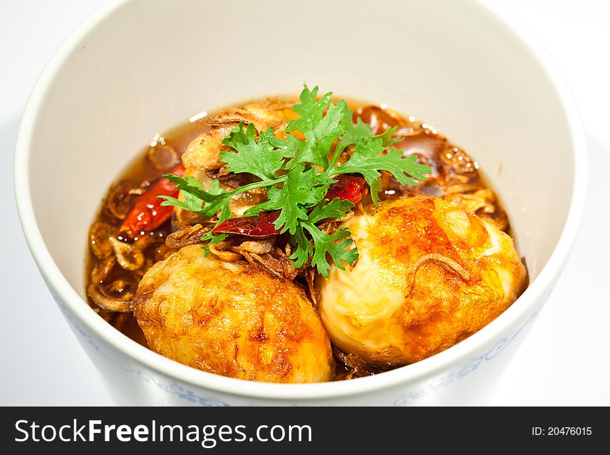 Fried eggs topped with sweet sauce on white background