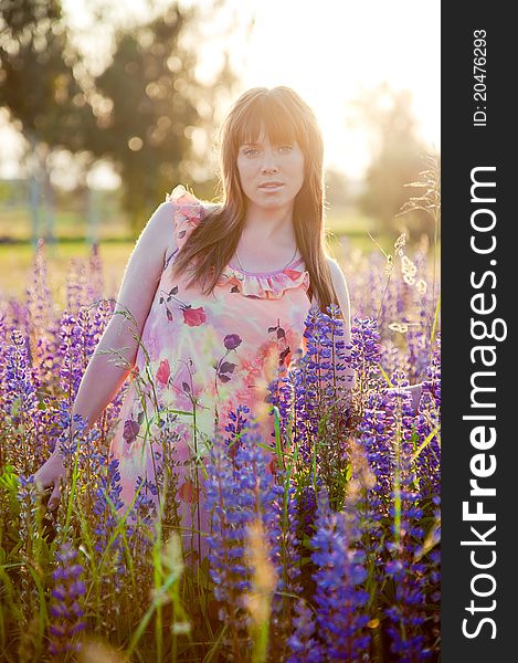 Pretty young woman is at the fild with beautiful lilac flowers on the sunset. Pretty young woman is at the fild with beautiful lilac flowers on the sunset