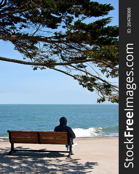 A man is sitting on a bench and looking to the sea. A man is sitting on a bench and looking to the sea