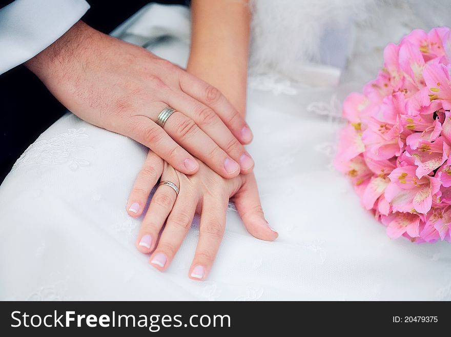 Hands with rings and wedding bouquet