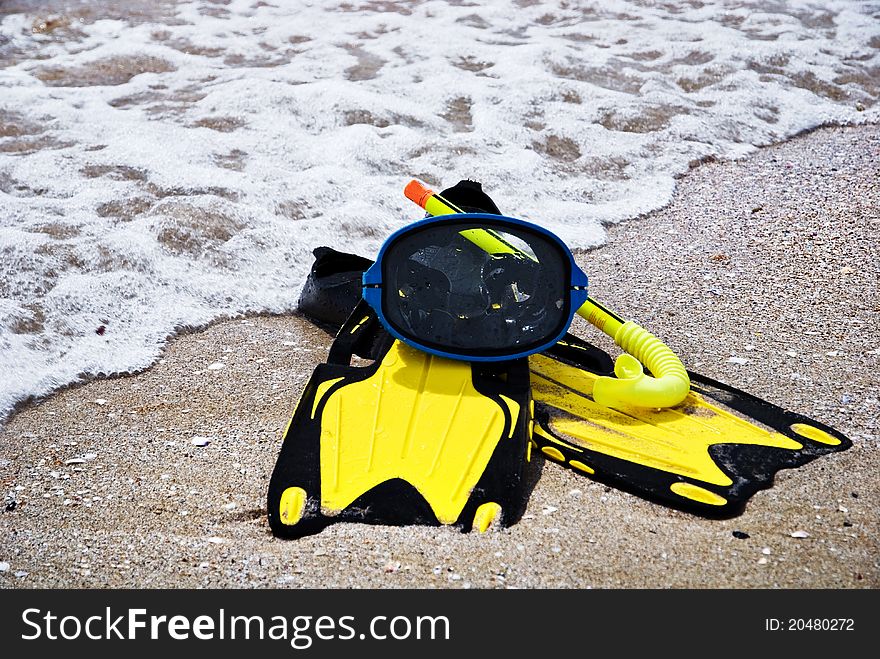Yellow flippers and swimming mask on the sandy beach of sea. Yellow flippers and swimming mask on the sandy beach of sea