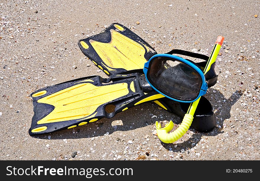 Yellow flippers and swimming mask on sea beach