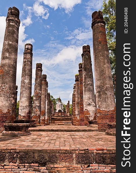 Ruin Buddha statue among ruin pillars in Sukhothai historic park from back worm vertical. Ruin Buddha statue among ruin pillars in Sukhothai historic park from back worm vertical