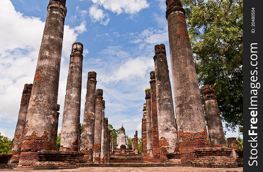 Ruin Buddha statue among ruin pillars in Sukhothai historic park from back worm. Ruin Buddha statue among ruin pillars in Sukhothai historic park from back worm